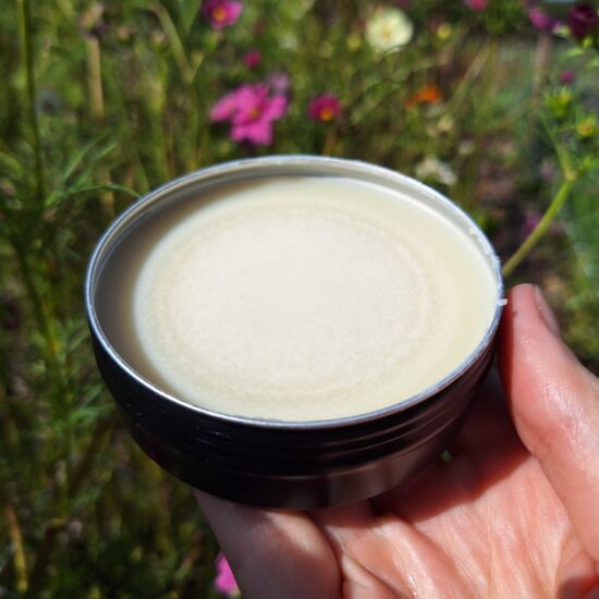 Hand houdt natuurlijke balsem in de zon voor planten